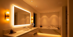 Modern bathroom with layered warm lighting, backlit mirror, and recessed ceiling lights creating a spa-like ambient mood