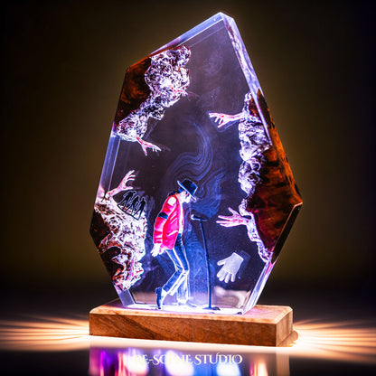 Handmade epoxy resin table lamp showing a dancer in a fedora and red jacket in a dramatic forward anti-gravity lean with reaching shadow hands, on a wood LED base (view 2)