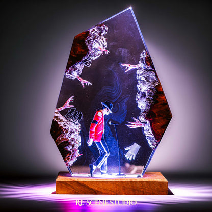 Handmade epoxy resin table lamp showing a dancer in a fedora and red jacket in a dramatic forward anti-gravity lean with reaching shadow hands, on a wood LED base (view 1)
