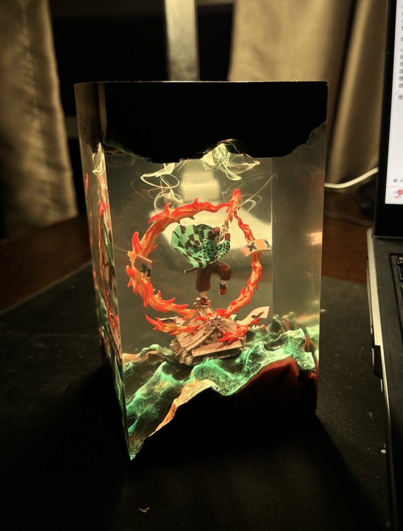 Decorative glass piece with red and green design on a dark surface